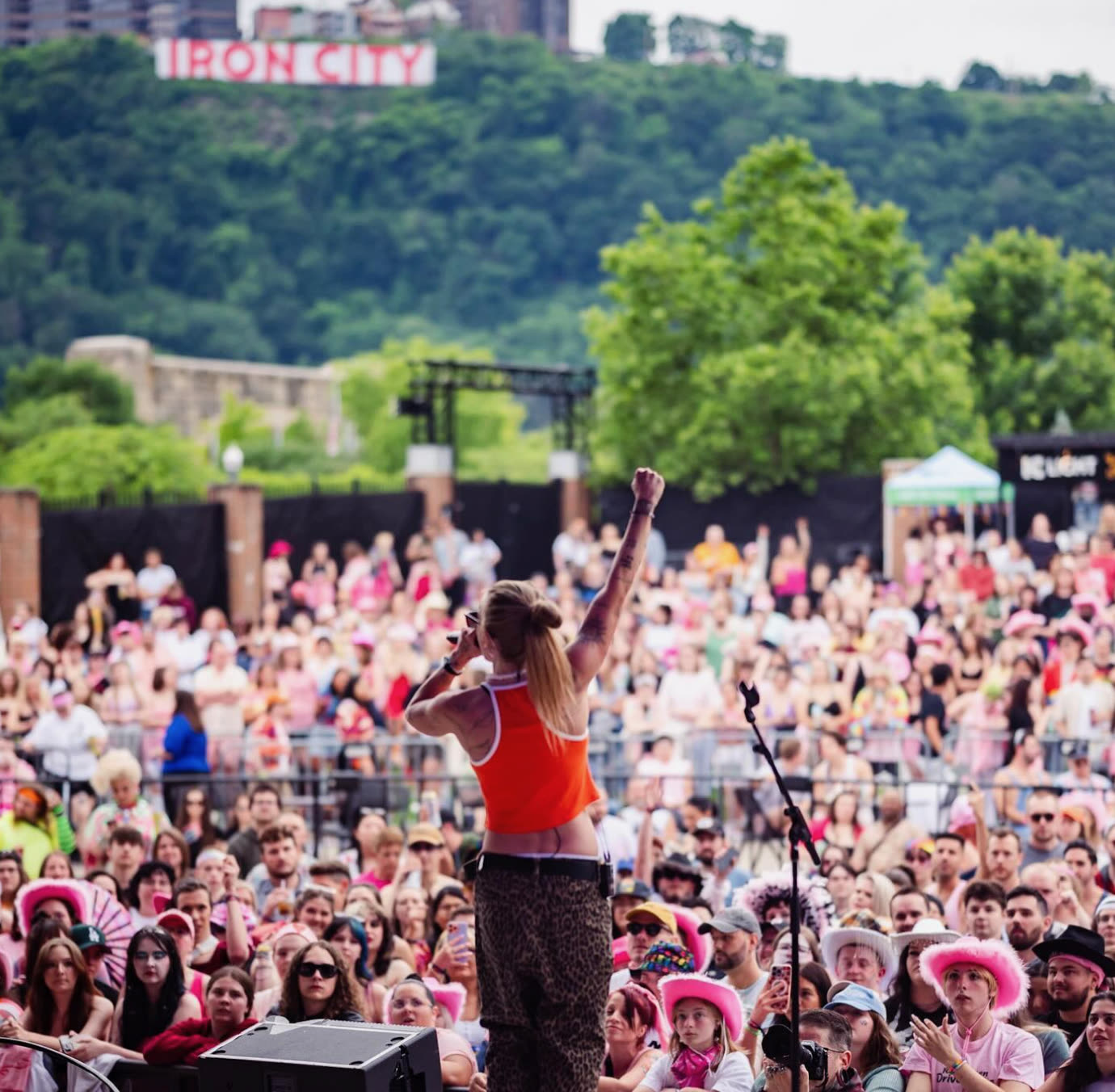 Performer on stage at All Out Music Festival with the crowd and Pittsburgh’s Iron City sign in the background